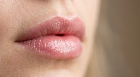Primo piano di labbra femminili naturalmente voluminose con texture morbida e luminosità naturale