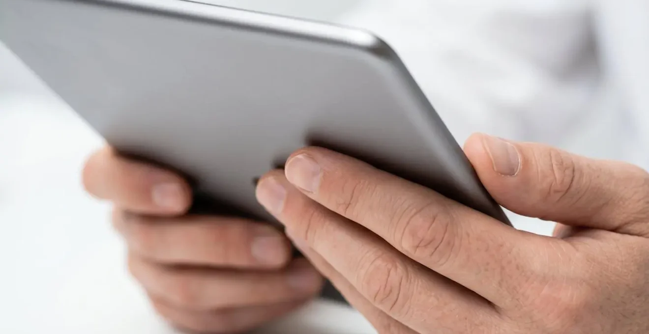 Mani che consultano un tablet per verificare credenziali mediche online